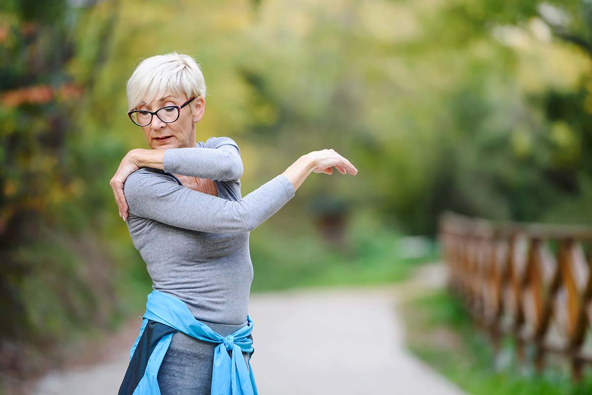 Senior woman stretching outdoors, promoting osteoporosis awareness